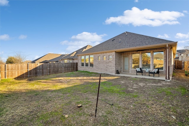 back of property with brick siding, a patio, a shingled roof, a lawn, and a fenced backyard