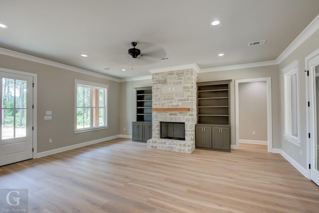 unfurnished living room with a stone fireplace, crown molding, light hardwood / wood-style flooring, built in features, and ceiling fan