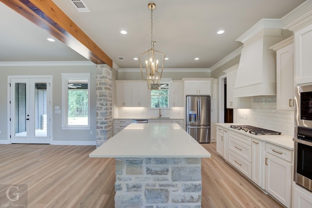 kitchen featuring white cabinets, a center island, custom range hood, and stainless steel appliances