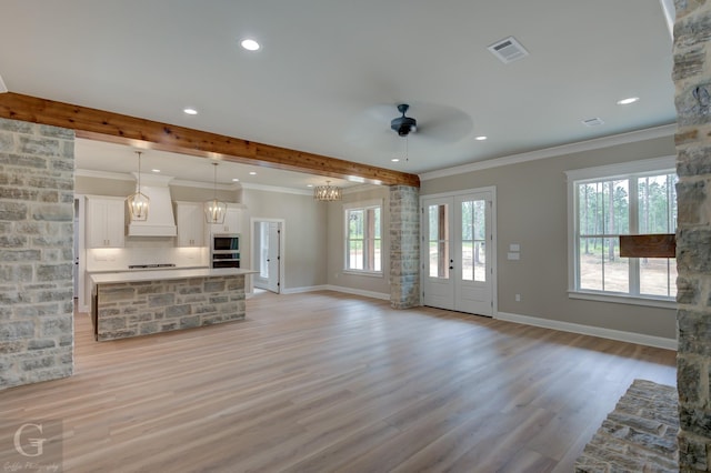 unfurnished living room featuring crown molding, ceiling fan with notable chandelier, and light hardwood / wood-style flooring