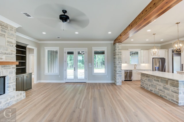 kitchen featuring a fireplace, white cabinets, pendant lighting, and appliances with stainless steel finishes