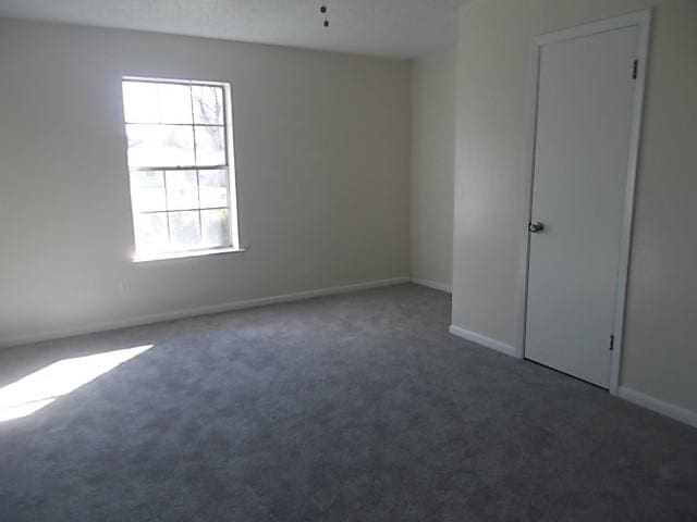 spare room featuring a healthy amount of sunlight and dark colored carpet