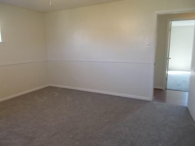 empty room featuring ceiling fan and dark colored carpet