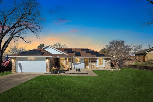 view of front of home featuring a yard, a garage, and solar panels