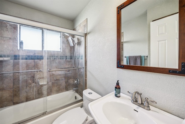 full bathroom featuring sink, shower / bath combination with glass door, and toilet