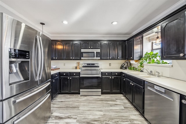 kitchen with sink, hanging light fixtures, ornamental molding, appliances with stainless steel finishes, and light hardwood / wood-style floors