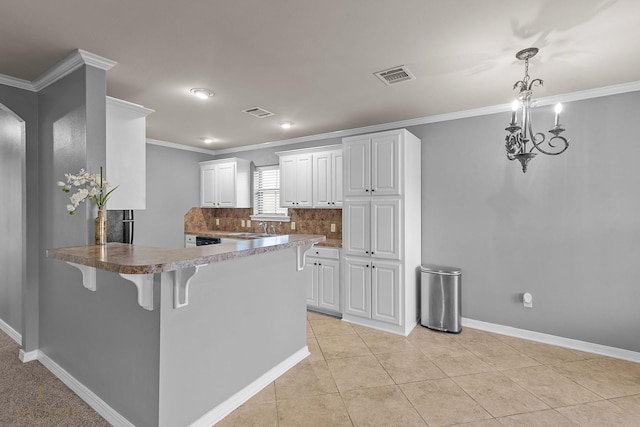 kitchen featuring a kitchen bar, white cabinetry, tasteful backsplash, light tile patterned floors, and kitchen peninsula