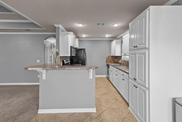 kitchen featuring white cabinetry, backsplash, black appliances, a kitchen bar, and kitchen peninsula