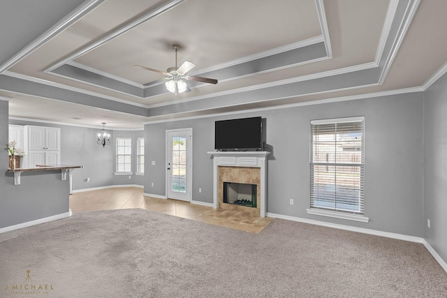 unfurnished living room with a raised ceiling, crown molding, light colored carpet, and a tile fireplace