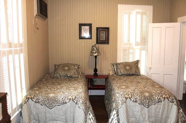 bedroom with an AC wall unit and wooden walls