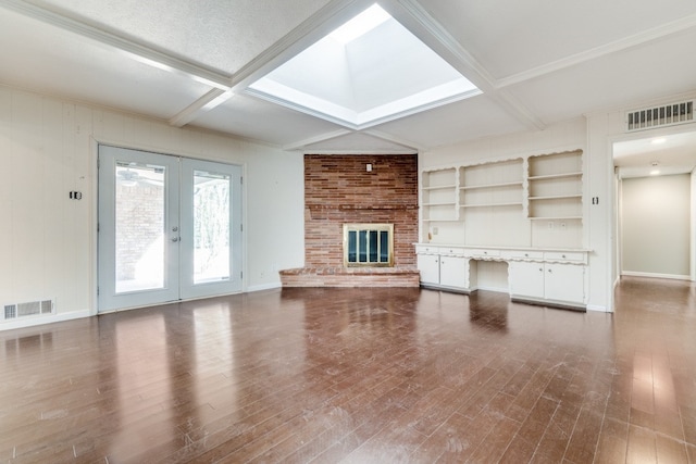 unfurnished living room featuring coffered ceiling, hardwood / wood-style flooring, a brick fireplace, french doors, and beam ceiling