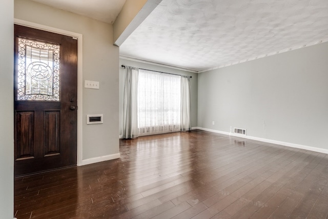 foyer entrance featuring a textured ceiling and dark hardwood / wood-style floors