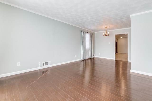 empty room featuring crown molding, dark hardwood / wood-style floors, and a notable chandelier