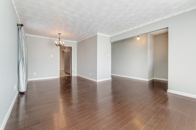 spare room with an inviting chandelier, a textured ceiling, dark wood-type flooring, and ornamental molding