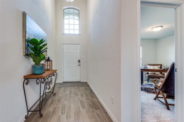 foyer entrance with light hardwood / wood-style floors and a towering ceiling