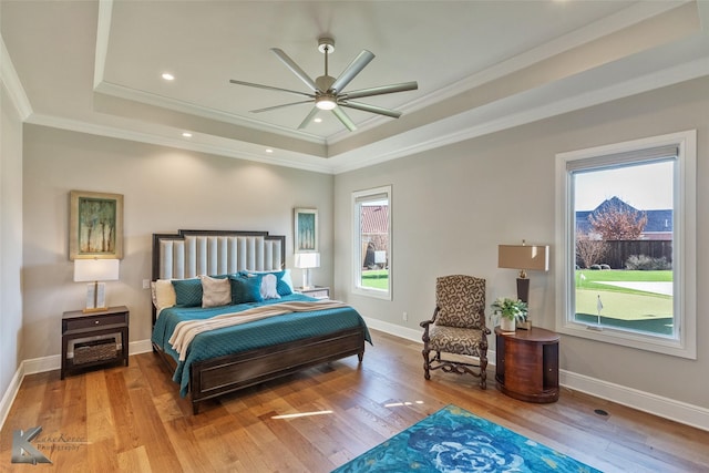 bedroom with ceiling fan, crown molding, light hardwood / wood-style flooring, and a raised ceiling