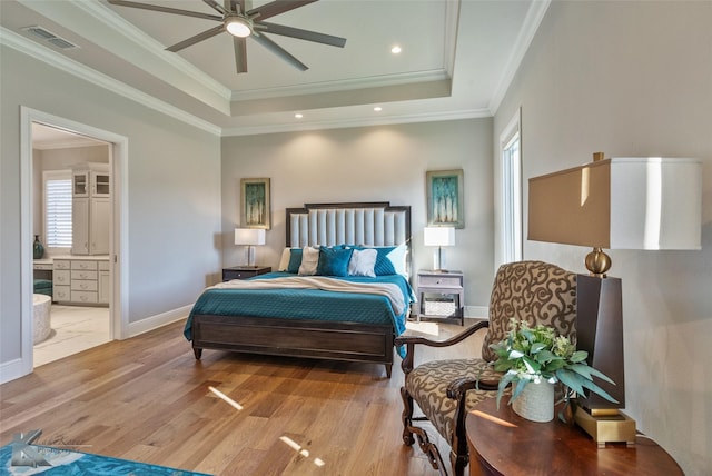 bedroom with crown molding, ensuite bathroom, ceiling fan, a raised ceiling, and light wood-type flooring