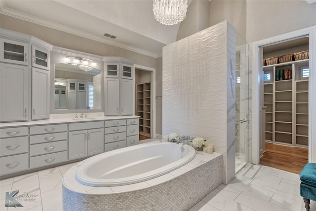 bathroom featuring ornamental molding, separate shower and tub, a notable chandelier, and vanity