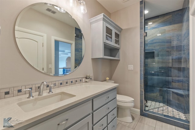 bathroom featuring vanity, toilet, walk in shower, and backsplash