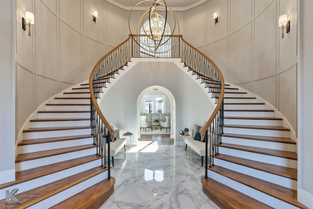 stairway with a chandelier and crown molding