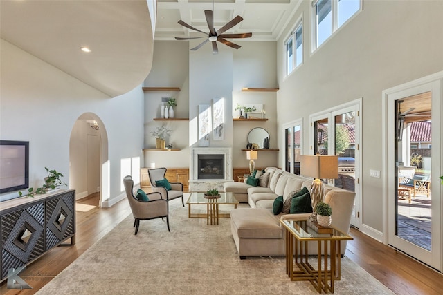 living room featuring coffered ceiling, beamed ceiling, light hardwood / wood-style flooring, and a towering ceiling