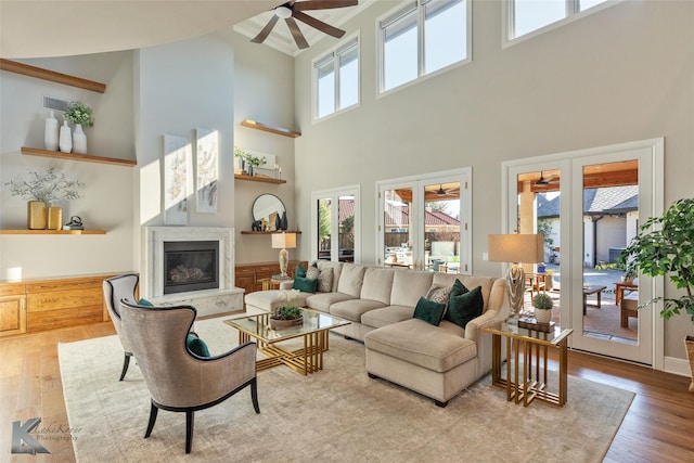 living room featuring a towering ceiling, plenty of natural light, light hardwood / wood-style flooring, and a premium fireplace