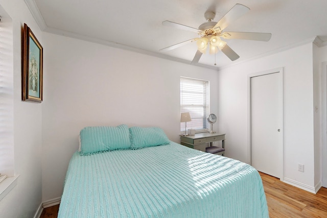 bedroom with crown molding, ceiling fan, a closet, and light wood-type flooring