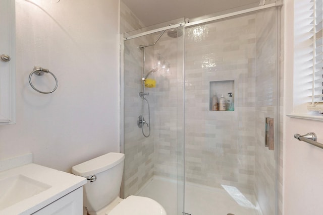 bathroom featuring vanity, a shower with shower door, and toilet