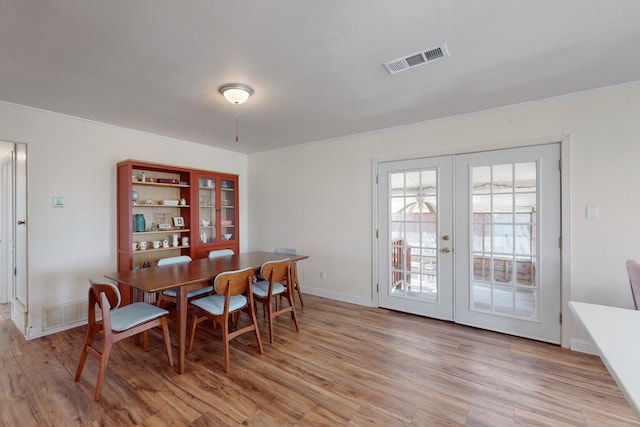 dining area with french doors and light hardwood / wood-style flooring