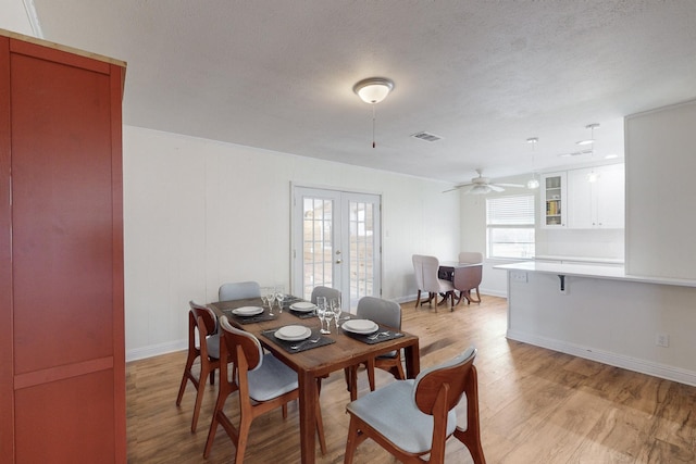 dining room featuring ceiling fan, light hardwood / wood-style flooring, a textured ceiling, and french doors