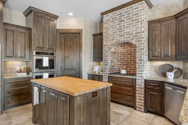 kitchen featuring a kitchen island, dark brown cabinetry, butcher block countertops, and stainless steel appliances