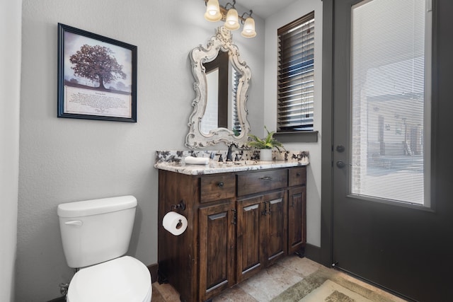 bathroom featuring toilet, stone finish floor, and vanity