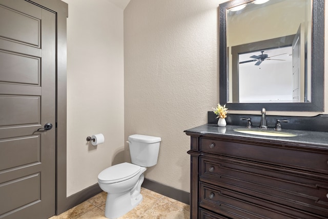 half bathroom with vanity, baseboards, and toilet