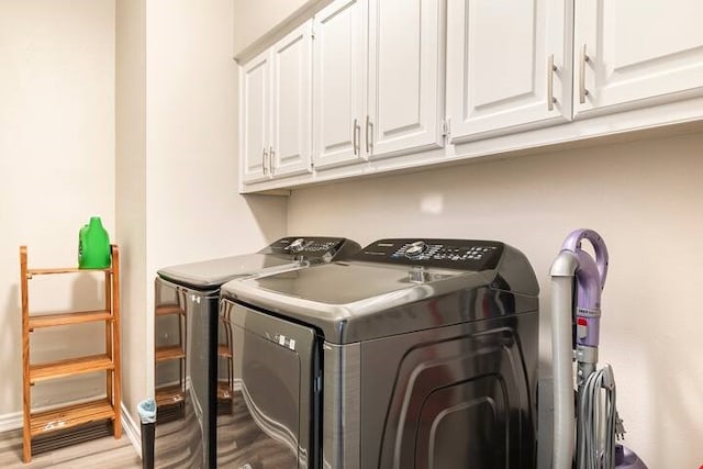 clothes washing area with cabinets, washing machine and dryer, and light hardwood / wood-style floors