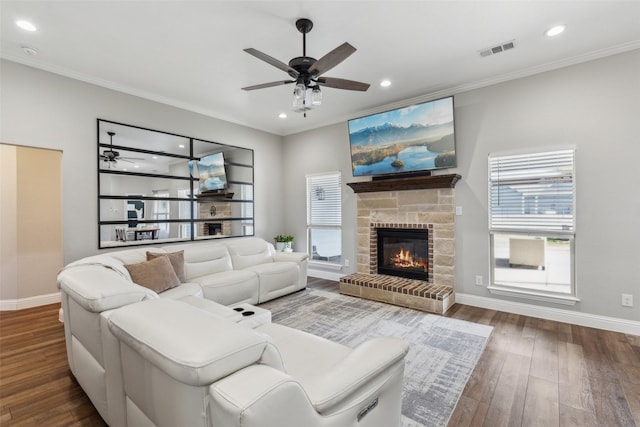 living room featuring crown molding, a fireplace, dark hardwood / wood-style floors, and ceiling fan