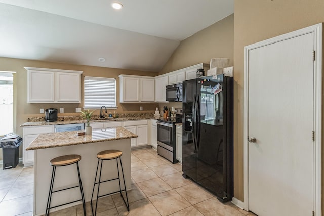 kitchen featuring vaulted ceiling, white cabinetry, a wealth of natural light, a kitchen island, and black appliances