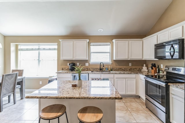 kitchen featuring a center island, light stone countertops, stainless steel electric range oven, white cabinetry, and sink