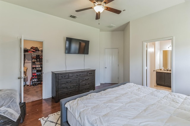 bedroom featuring wood-type flooring, ceiling fan, a walk in closet, connected bathroom, and a closet