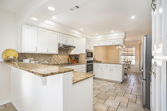 kitchen featuring stone countertops, kitchen peninsula, white cabinets, stainless steel appliances, and backsplash