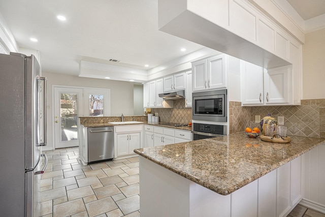 kitchen with sink, white cabinetry, appliances with stainless steel finishes, kitchen peninsula, and light stone countertops