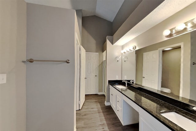 bathroom featuring hardwood / wood-style floors, toilet, vaulted ceiling, and vanity