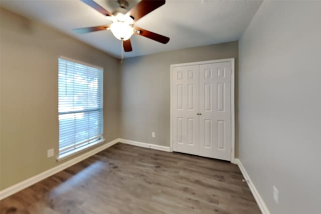 unfurnished bedroom with a closet, ceiling fan, and dark hardwood / wood-style floors