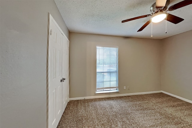 carpeted spare room featuring ceiling fan and a textured ceiling