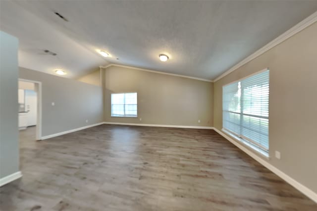 unfurnished room featuring plenty of natural light, hardwood / wood-style flooring, lofted ceiling, and ornamental molding