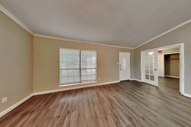 entryway with hardwood / wood-style flooring, a textured ceiling, ornamental molding, and vaulted ceiling