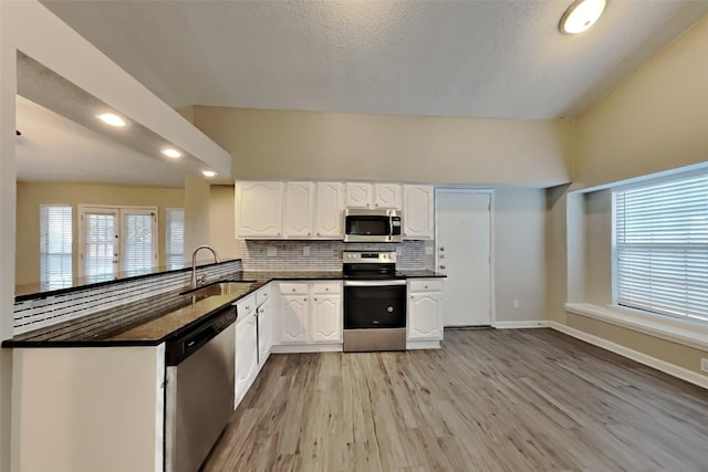 kitchen with white cabinets, sink, light hardwood / wood-style flooring, kitchen peninsula, and stainless steel appliances