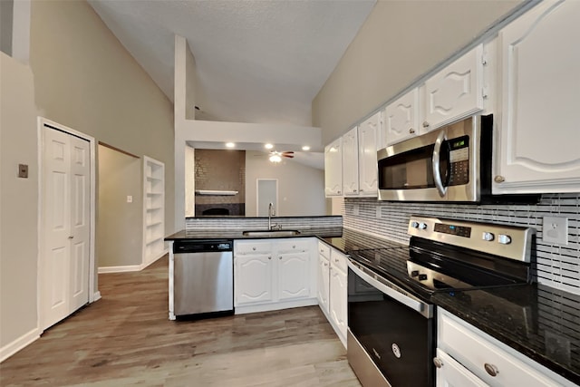 kitchen featuring white cabinets, appliances with stainless steel finishes, lofted ceiling, decorative backsplash, and sink