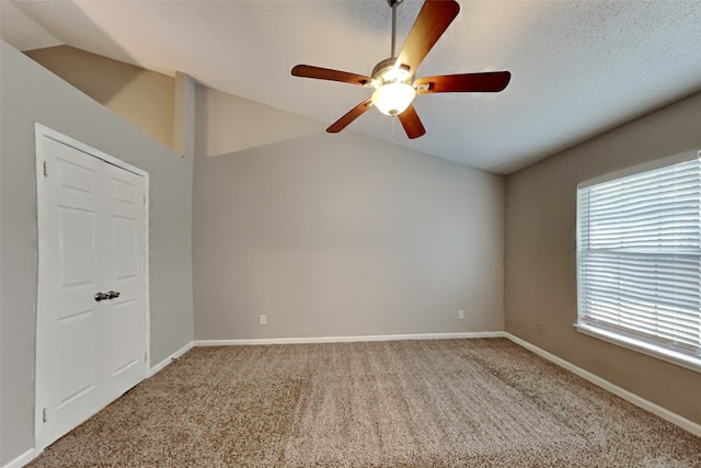 empty room featuring ceiling fan, carpet, a textured ceiling, and lofted ceiling