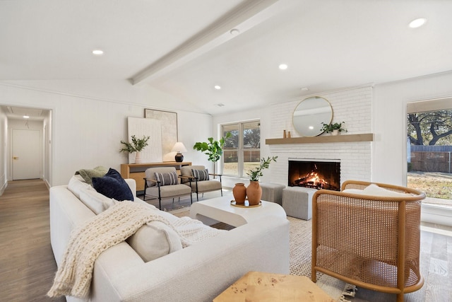 living room with hardwood / wood-style flooring, a brick fireplace, and lofted ceiling with beams