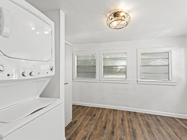 laundry area with dark hardwood / wood-style flooring and stacked washing maching and dryer